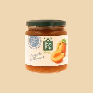 Vasetto di composta biologica Bio Più all’albicocca da 320g, con tappo verde e etichetta illustrata con albicocche mature.