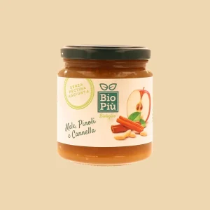 Vasetto di composta biologica Bio Più con mele, pinoli e cannella, etichetta illustrata con ingredienti naturali.